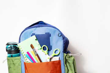 School backpack with stationery on a white background, a place for the text.