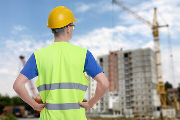 Young man wearing safety equipment at construction site, back view. Space for text