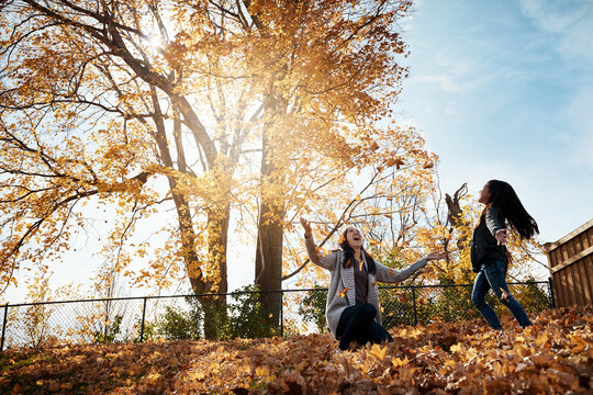 Autumn, mom and girl throwing leaves in garden of home together for bonding or love. Family, children or fall with single parent woman and happy daughter having fun in backyard for wellness.