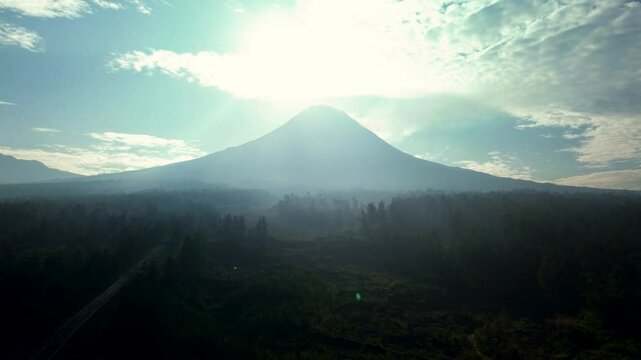 Aerial footage of the beauty of Mount Merapi at midday. Beautiful view of Mount Merapi with the sun directly above and only 7km away with lava flowing cliffs in the foreground