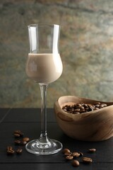 Coffee cream liqueur in glass and beans on black wooden table