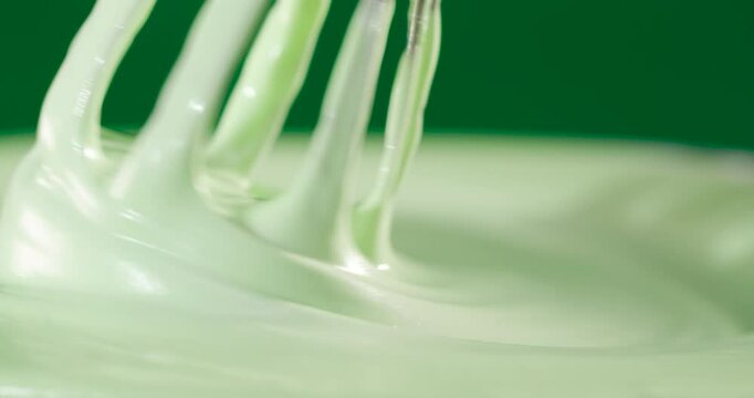 Finished green cream in rotation with a hand whisk on the green.
