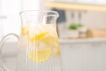 Freshly made lemonade in jug on table indoors, closeup. Space for text