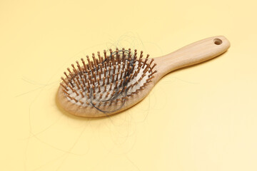 Wooden brush with lost hair on yellow background