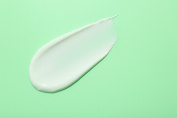 Sample of face cream on green background, top view. Space for text