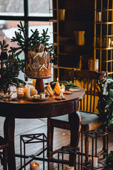 Elegant beautiful Christmas house decoration, stylish holiday decor. Homemade delicious sweet gingerbread house as centrepiece for family dinner. Fir tree branches, candles, stars, garlands