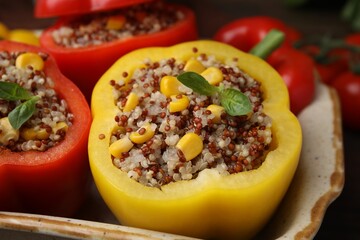 Quinoa stuffed bell peppers and basil in baking dish, closeup