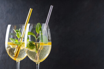 Hugo Spritz Cocktails in Glasses with Mint, Lemon and Cocktail Straws on Dark Background, Copy Space