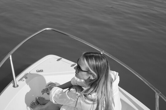 Woman on a yacht. 
Black and white photo of young woman at sailboat, relaxing at summer vacation.