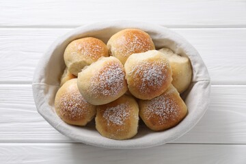 Delicious dough balls in basket on white wooden table, top view