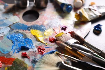 Obraz premium Artist's palette, brushes and paints on grey table, closeup