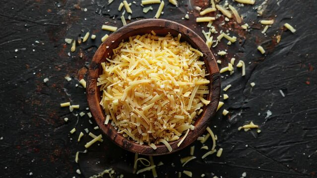 Top View of Grated Cheese in Wooden Bowl on Dark Background