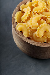 Raw Creste di Gallo Pasta in Wooden Bowl on Concrete Background, Copy Space