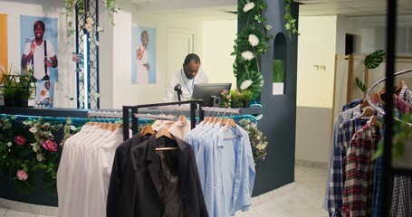 African american employee in retail store sorting out online orders from customers. Shopkeeper in clothing shop looking at digital device screen, fulfilling shopping deliveries needing to be sent