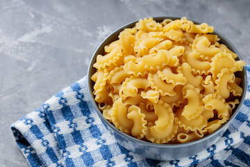 Uncooked Creste di Gallo Pasta in Bowl on Gray Concrete Background, Copy Space
