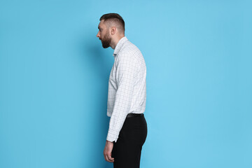 Man with poor posture on light blue background