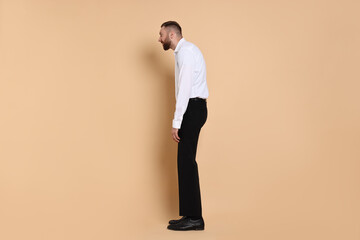 Man with poor posture on pale orange background