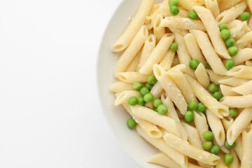 Delicious pasta with green peas and cheese in bowl on white background, top view. Space for text