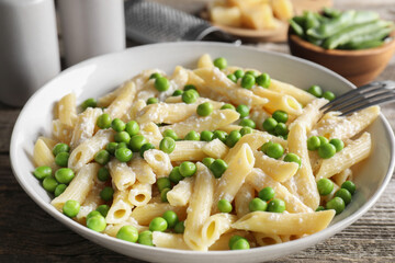 Delicious pasta with green peas and cheese on wooden table, closeup