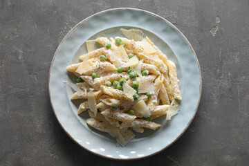 Delicious pasta with green peas, cheese and creamy sauce on grey table, top view