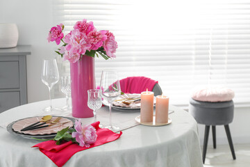 Beautiful table setting with pink peonies and burning candles