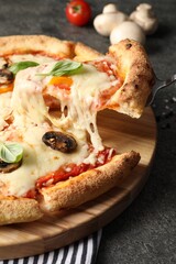 Taking piece of delicious vegetarian pizza at grey table, closeup