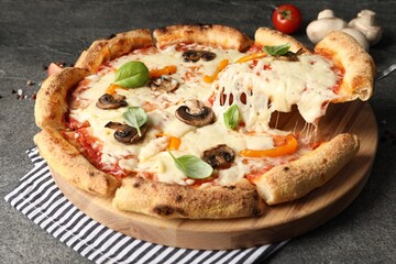 Taking piece of delicious vegetarian pizza at grey table, closeup