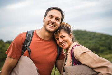 Portrait of boyfriend and girlfriend smile and hold backpacks for camp