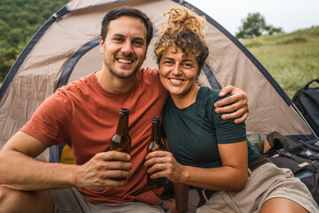 Portrait of happy smile couple with bottle of beer on camp