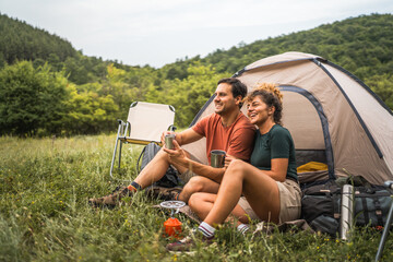 couple in love sit on the grass enjoy camp with coffee and talk