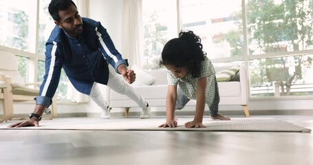 Sporty young father training active strong little Indian daughter girl, teaching pushups with friendly fist bump gesture, enjoying exercise, home fitness, fatherhood, healthy lifestyle