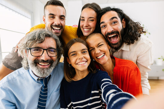 Happy caucasian family talking selfie portrait together at home. Multigenerational group of people smiling at camera standing gathered at domestic room.