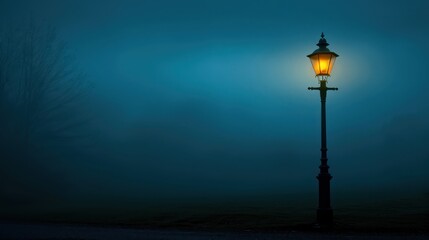 Old-fashioned lamp post lighting up the misty night in the dark.