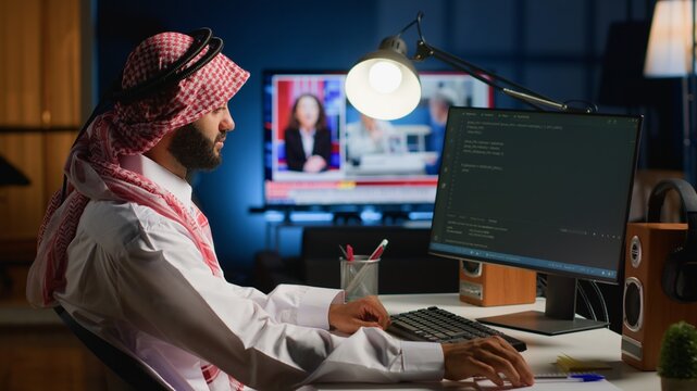 Licensed muslim engineer writing code on computer screen while in office using Java programming languages. Middle Eastern developer working on fixing database errors while working from living room