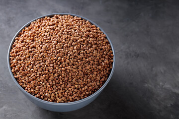 Organic Dry Buckwheat Grains in Bowl on Concrete, Copy Space