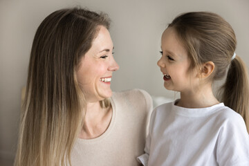 Close up side profile faces view of young 30s loving mother and beautiful preschooler daughter...