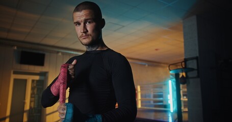 Focused Male Boxer with Tattoos Standing in Gym, Preparing Mentally Before Training