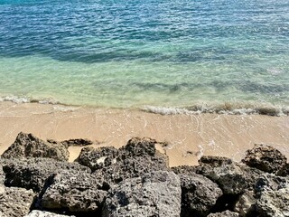 close-up of a small wild sandy beach with rocks and a turquoise sea in Guadeloupe in the French West Indies on a sunny day
