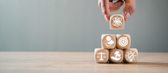 Hand stacking wooden blocks with icons symbolizing core values such as innovation, balance, and...