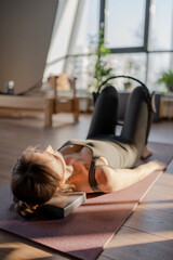 A woman is using a hip Magic Circle at Glute bridge Pilates workout in studio, being active and committed to exercising
