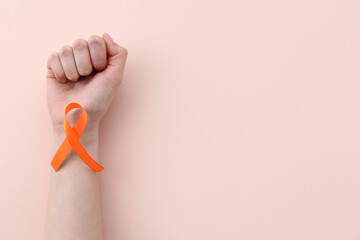 Woman with orange awareness ribbon on beige background, top view. Space for text