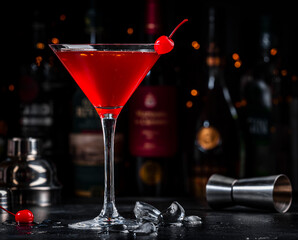 Red alcoholic cocktail drink with cherry on dark background, bar counter with bottles
