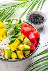 Poke bowl for balanced dietl with tuna, avocado, mango, cucumber, lettuce and rice, soy sauce and sesame seeds. White background, top view