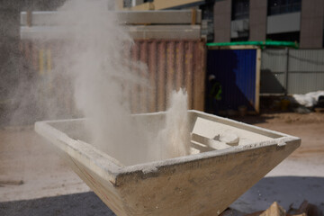 Dust is billowing up at a construction site where workers are busy with industrial cement tasks