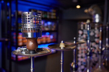 Close up of a hookah made of metal and glass on a wooden table