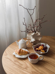 Tea party set table - tea, croissant, fruits and berries on a round wooden table