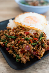 Stir fried Thai basil with minced pork and a fried egg eating with cooked rice.