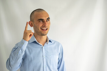 Young man having an idea while smiling. Businessman pointing up