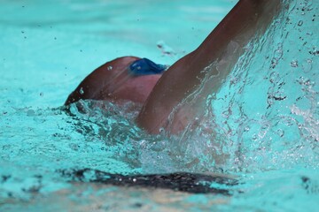 Eight (8) year old boy learning to swim. Summer, crystal clear blue water, swimming goggles, splash, holiday, active lifestyle, exercise.