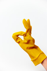 Person in yellow rubber glove making okay sign on white background